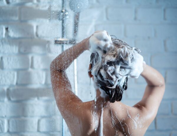 Femme se lavant les cheveux avec un shampoing sec dans une douche