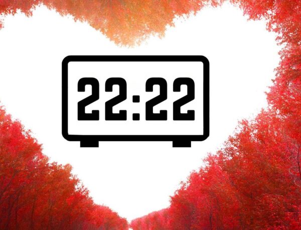 Heure miroir 22:22 affichée sur un réveil digital encadré par des arbres rouges formant une forme de cœur.